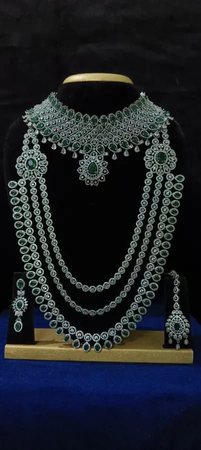 American diamond bridal jewellery set on a display stand — choker and four-strand long haram with jhumka, with green stones