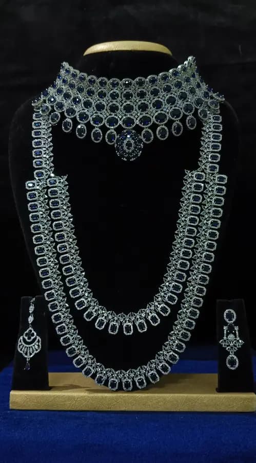 American diamond bridal jewellery set on a display stand — short necklace, long haram and jhumka, with green stones
