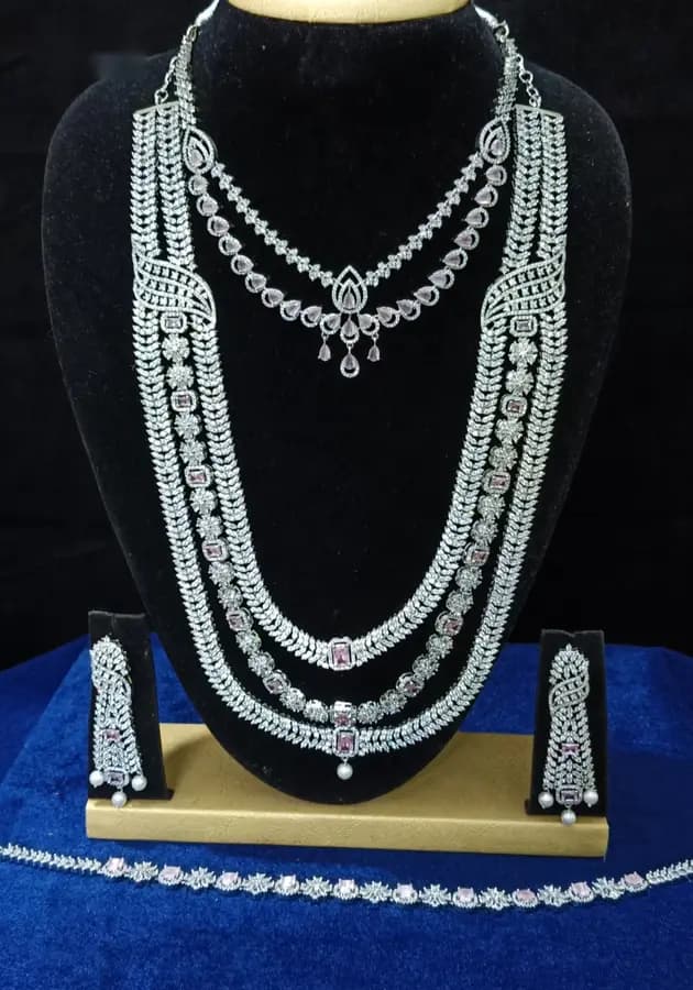 American diamond bridal jewellery set on a display stand — short necklace, four-strand long haram, jhumka and oddiyanam, with white stones