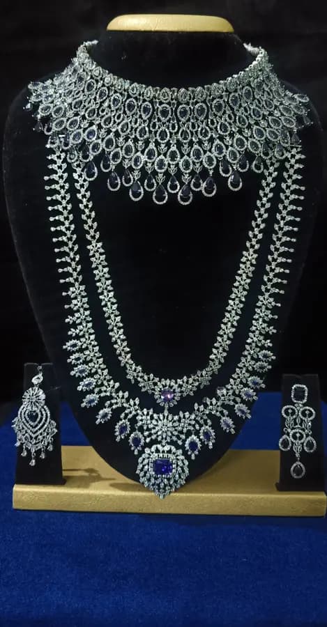 American diamond bridal jewellery set on a display stand — choker, long haram and jhumka, with a blue centre stone