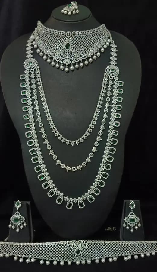 American diamond bridal jewellery set on a display stand — short necklace, long haram, jhumka and oddiyanam, with white stones