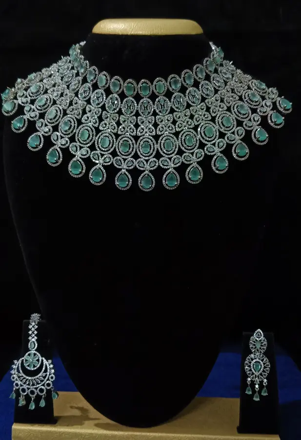 Stone-set bridal choker necklace with matching earrings on a display stand