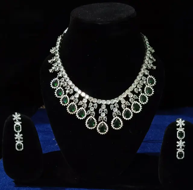 Stone-set bridal choker and earrings on a display stand — a necklace with matching earrings, with green drops
