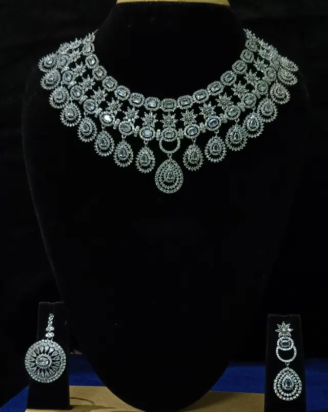 Stone-set bridal choker and earrings on a display stand — a wide necklace with matching earrings, with white stones