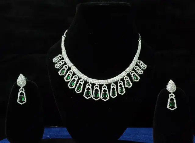 Stone-set bridal choker and earrings on a display stand — a necklace with matching earrings, with green drops