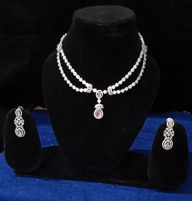 Stone-set bridal choker and earrings on a display stand — a two-strand necklace with matching earrings, with a pink centre stone