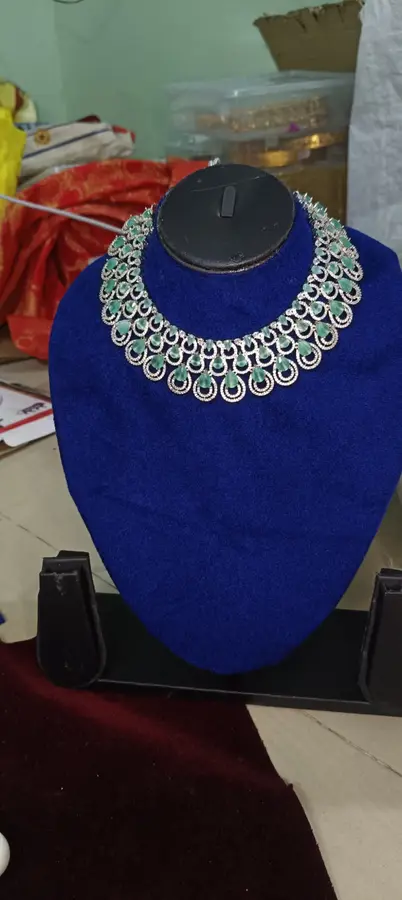 Stone-set bridal choker and earrings on a display stand — a wide choker on a blue stand, with white stones