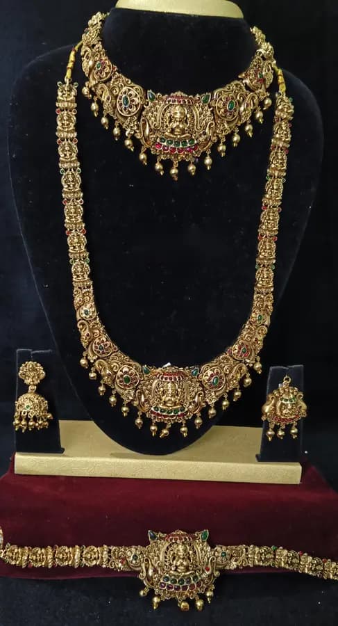 Antique gold-toned temple jewellery bridal set — long haram, short necklace and jhumka on a display stand