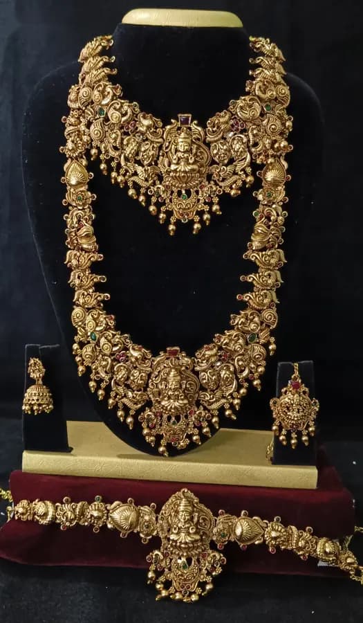 Antique gold-toned temple jewellery bridal set — long haram, short necklace and jhumka on a display stand
