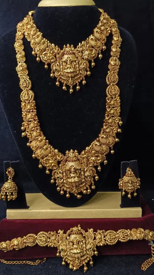 Antique gold-toned temple jewellery bridal set — long haram, short necklace and jhumka on a display stand