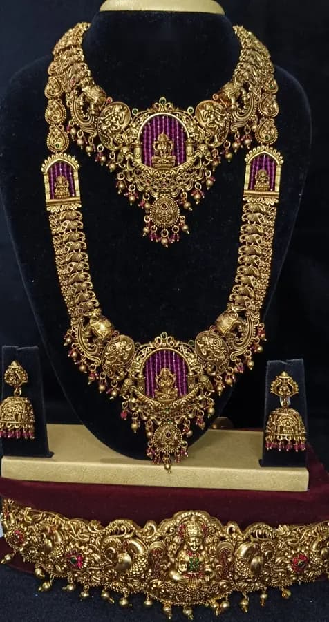 Antique gold-toned temple jewellery bridal set — long haram, short necklace and jhumka on a display stand