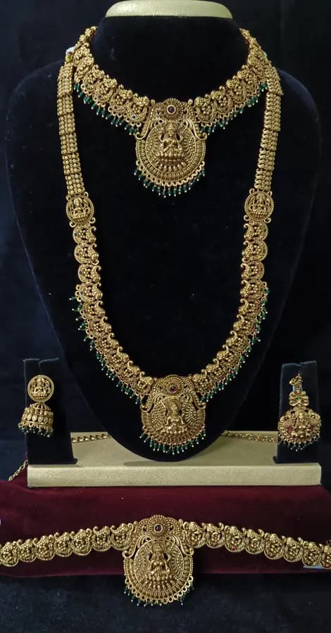 Antique gold-toned temple jewellery bridal set — long haram, short necklace and jhumka on a display stand
