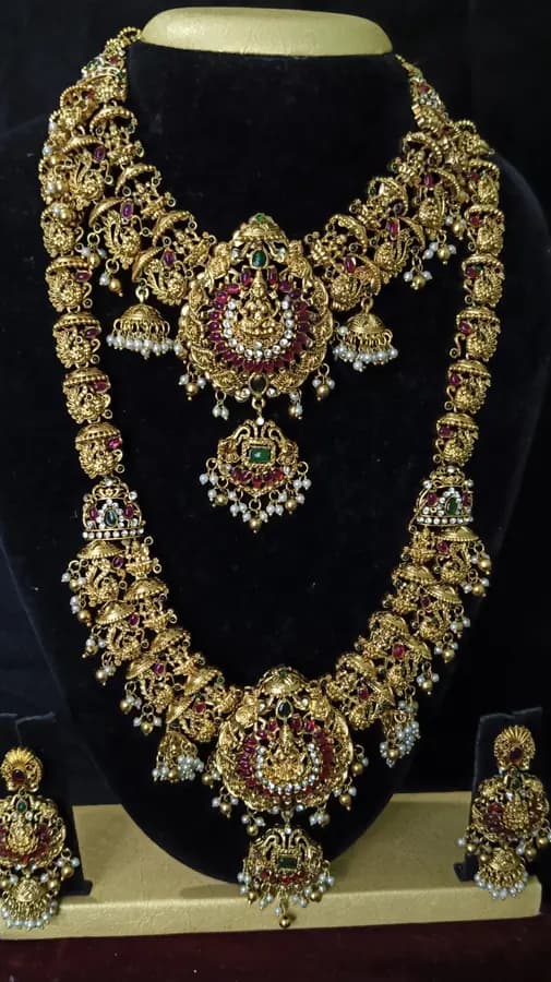 Antique gold-toned temple jewellery bridal set — long haram, short necklace and jhumka on a display stand