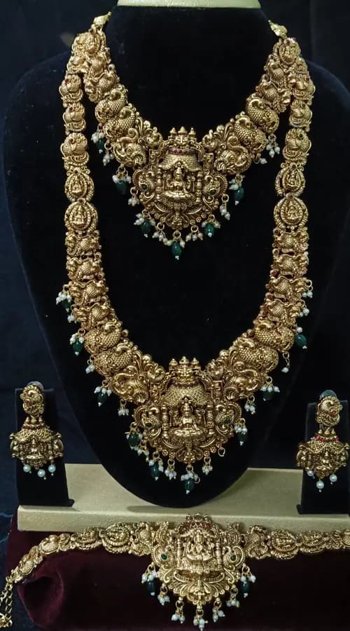 Antique gold-toned temple jewellery bridal set — long haram, short necklace and jhumka on a display stand