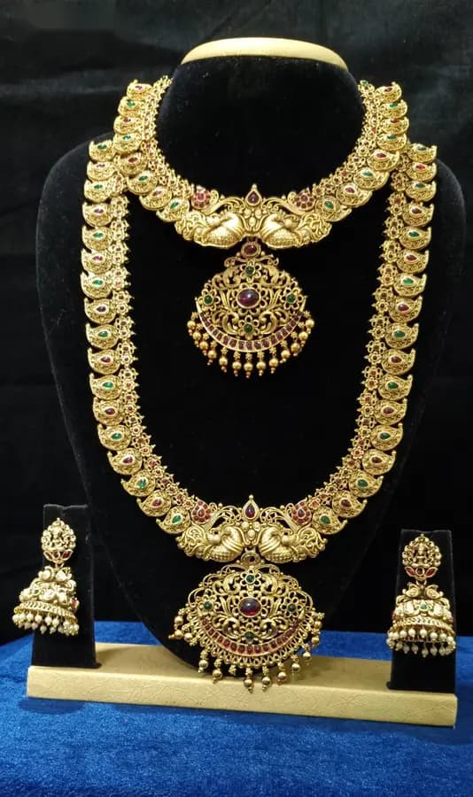 Antique gold-toned temple jewellery bridal set — long haram, short necklace and jhumka on a display stand