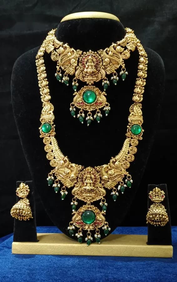 Antique gold-toned temple jewellery bridal set — long haram, short necklace and jhumka on a display stand