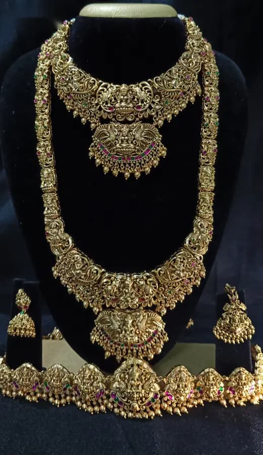 Antique gold-toned temple jewellery bridal set — long haram, short necklace and jhumka on a display stand