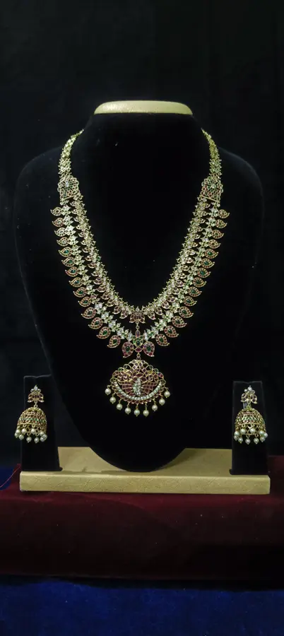 Antique gold temple jewellery bridal set on a display stand — a single long haram and jhumka