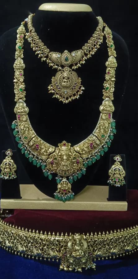 Antique gold temple jewellery bridal set on a display stand — short necklace, long haram, jhumka and oddiyanam, with turquoise drops