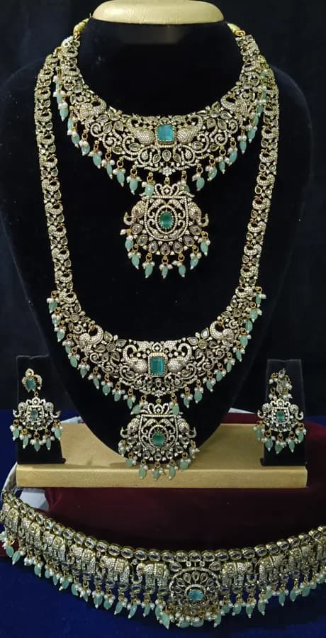 Antique gold temple jewellery bridal set on a display stand — short necklace, long haram, jhumka and oddiyanam, with a turquoise centre
